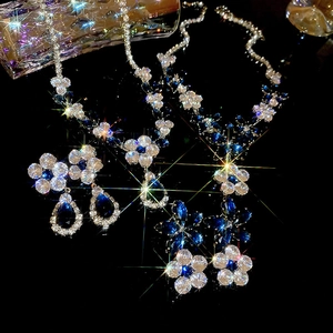 Close-up of floral silver necklace and teardrop earrings with blue and clear zircon stones