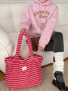Pink and red striped plush tote bag with dots pattern held by a model in pink hoodie