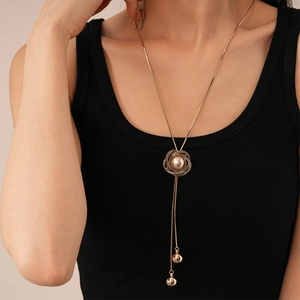Détail du pendentif fleur vintage avec perle champagne et pompons sur long collier doré