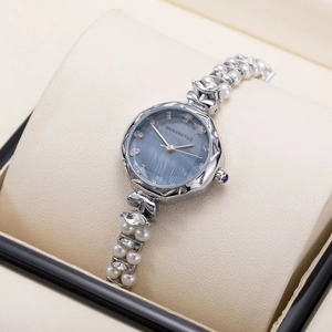 Detailed view of women's watch with blue mother-of-pearl dial and pearl bracelet