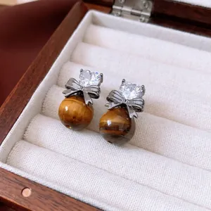 Retro tiger eye stone heart earrings with bow detail and zircon on a luxury jewelry box