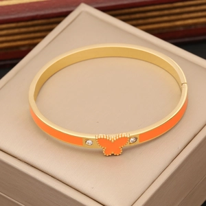 Detail of a golden butterfly bangle with orange enamel and sparkling white zircon stones