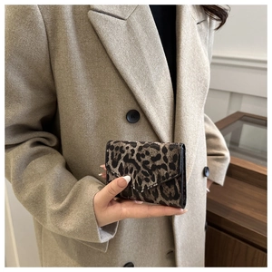 Dettaglio del portafoglio leopardato a busta tenuto da una modella con cappotto di lana