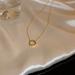 Dettaglio di un ciondolo circolare dorato su seta bianca con eleganti decori in vetro
