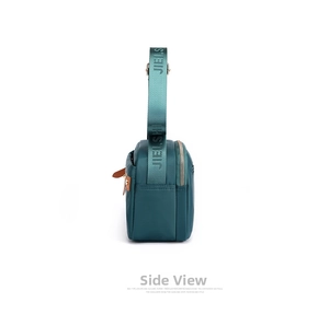 Detail view of the side profile on a dark green nylon crossbody bag with silver zippers