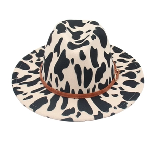 Cow print fedora hat with wide brim and brown faux leather belt featuring golden buckle