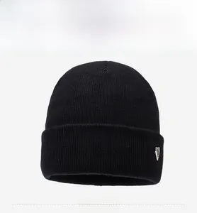 Detail of black knit beanie featuring silver triangle metal logo and ribbed texture