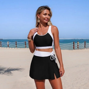 Detail of a two-piece black and white swimwear with drawstring side slit skirt on a beach