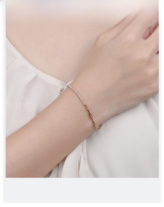 Detail of asymmetric gold bracelet featuring pave crystals and paperclip link design