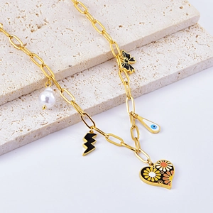 Collier en acier titane avec pendentif cœur, nœud et perles sur pierre beige