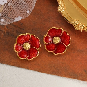 Detail of vintage red enamel flower earrings with golden edges on a retro background