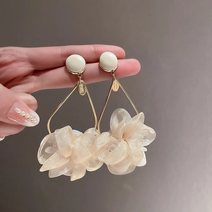Elegant gold triangle earrings with cream fabric flower petals held by hand