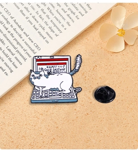 Detail of a white cat laptop enamel pin with Good Day text on a textured beige background