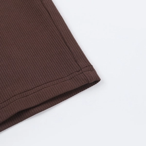 Gros plan sur le tissu en maille côtelée marron foncé et coutures détaillées d'une robe