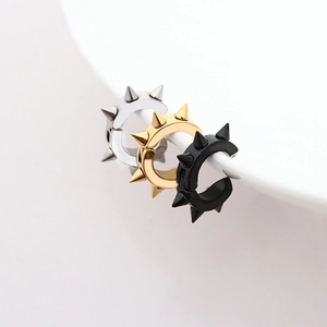 Three rivet-style punk ear cuffs in silver, gold, and black finishes on a white bowl
