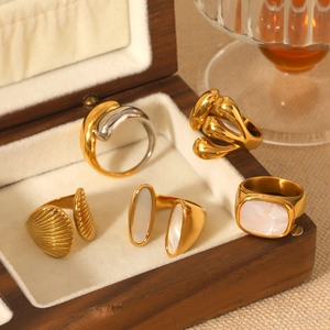 Golden rings with white shell inlay displayed on a wooden jewelry box in warm light