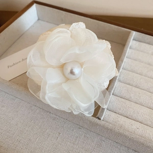 Vue détaillée de la pince à cheveux fleur en dentelle blanche avec perle centrale nacrée