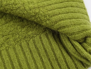 Detail of green knit cardigan showing ribbed texture and soft fuzzy wool fabric