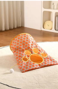 Detailed view of orange pattern cat tunnel with plush ball and paw-shaped window
