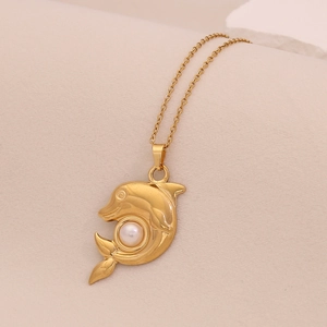 Detailed close-up of golden dolphin pendant with central pearl on fine chain necklace