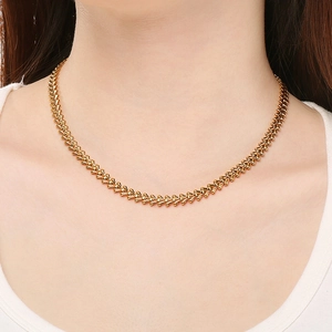 Detail of 18k gold plated wheat chain necklace on model showing its refined metallic texture