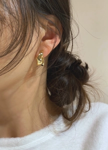 Close-up of a gold irregular lava-style hoop earring on a model with minimalist design