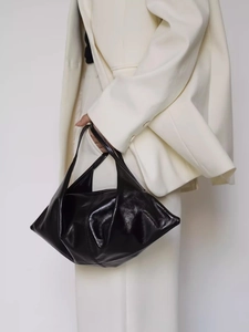 Minimalist black oil wax leather shoulder bag with glossy texture and slouchy crescent shape