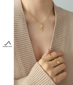 Detail of rose pendant necklace and gold rings set in stainless steel on model