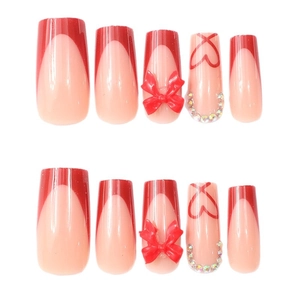 Faux ongles French rouges avec nœuds 3D et motifs cœurs en strass brillants
