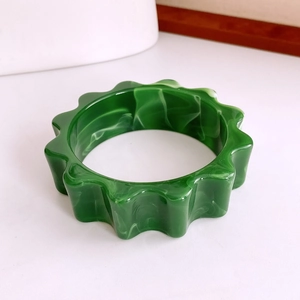 Détail d'un bracelet en acrylique vert à motif marbré avec bords ondulés