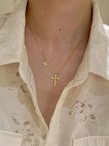 Detail of 24K gold plated cross pendant necklace worn on neck with beige lace shirt