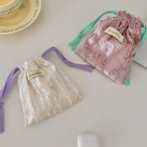Close-up of velvet drawstring pouch with delicate lace trim in pink and off-white colors