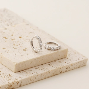 Detail of silver S925 huggie hoop earrings with sparkling cubic zirconia on stone base