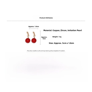 Macro view of red pearl earrings with gold copper hooks and sparkling cubic zirconia stones