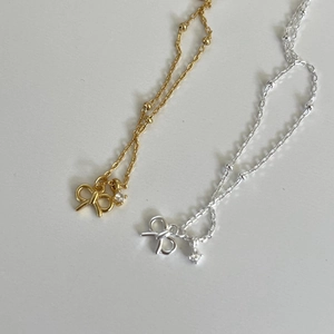 Close-up of gold and silver bow necklaces with sparkling cubic zirconia on white background