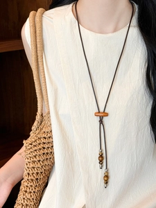 Detailed close-up of handmade coconut shell and wood bead necklace on a linen top