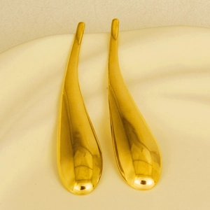 Macro detail showing gold-plated teardrop earrings with a polished mirror finish surface