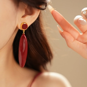 Gros plan de boucles d'oreilles élégantes en émail bordeaux avec monture dorée