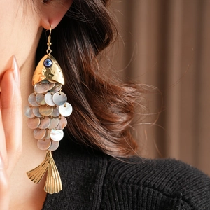 Macro side view of vintage fish drop earring with shell scales and evil eye detail