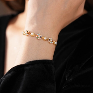 Close-up of vintage gold flower bracelet featuring pearls and colorful zircon stones
