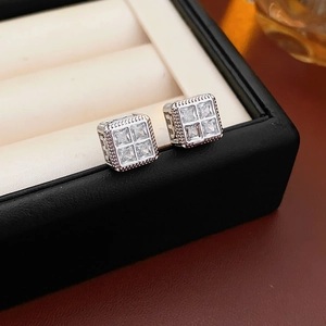 Vue macro de boucles d'oreilles carrées lettre M en argent avec zircons sur cuir noir