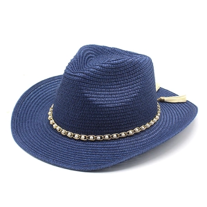 Detail of dark blue straw fedora with gold pearl chain and beige tassel accent