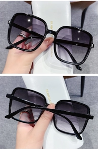 Detail of square black frame sunglasses with gradient grey lenses and premium glasses case