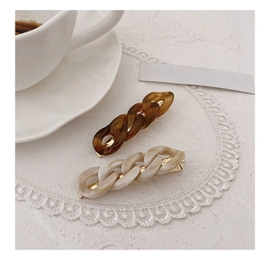 Detail of amber brown and marble white chain hair clips on elegant lace background