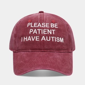 Close-up of white embroidery text on a washed burgundy vintage cotton baseball cap