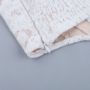 Detailed close-up of white lace bodice with concealed side zipper and intricate mesh stitching