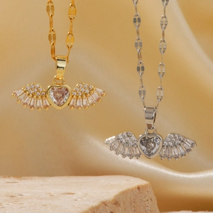 Elegant gold and silver heart-shaped angel wing necklaces on luxury silk background