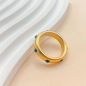 Détail d'une bague plaquée or 18 carats ornée de pierres précieuses facettées vert foncé