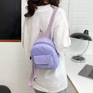 Detail of a purple corduroy mini backpack on model's back featuring adjustable straps