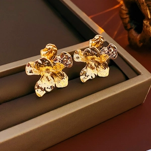 Detailed view of gold flower earrings with irregular wrinkled texture on a display box